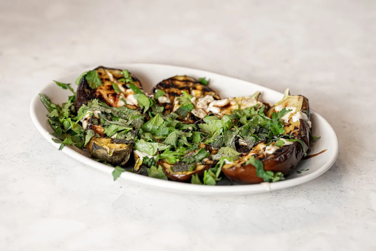 Grilled eggplant with a pale sauce and herbs