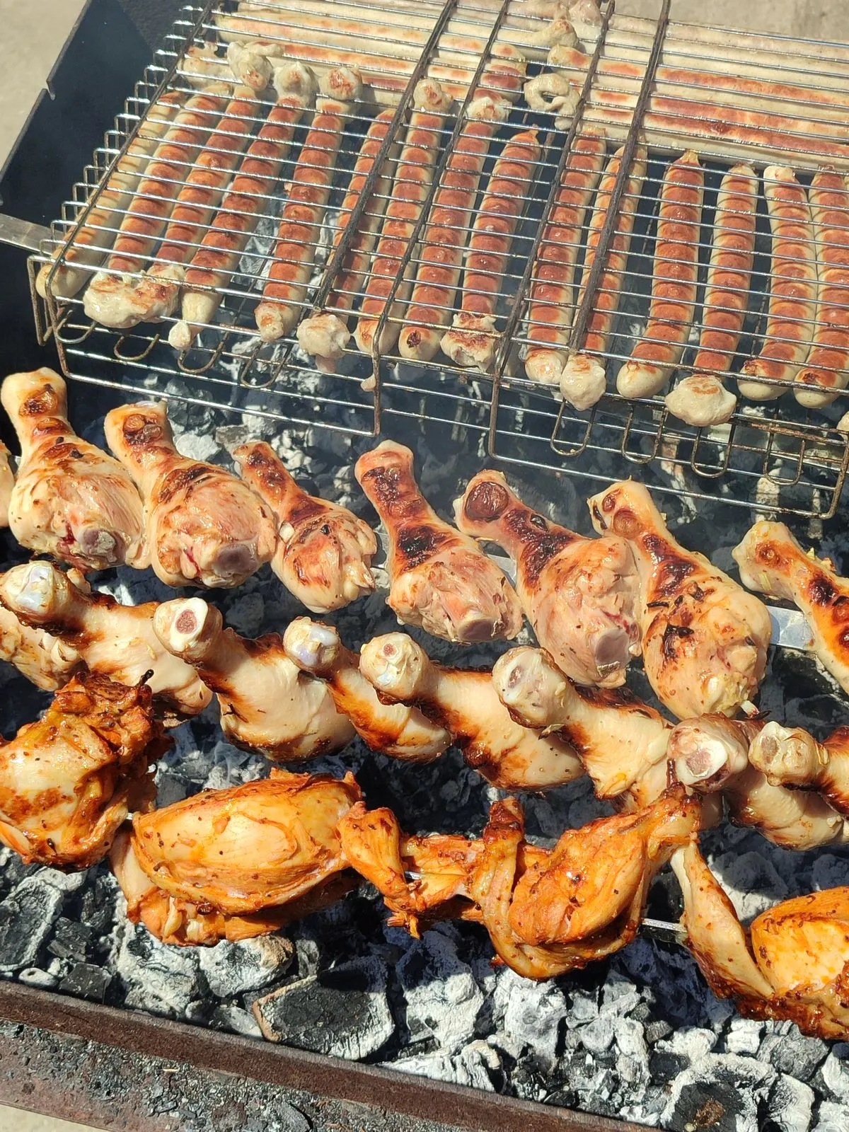 Chicken legs and sausages on a grill