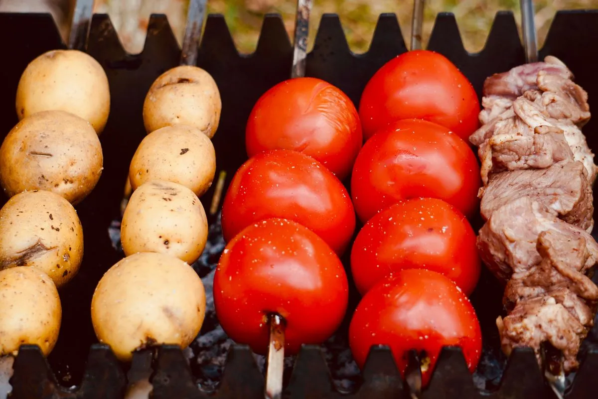 Potatoes and tomatoes cooking on a grill