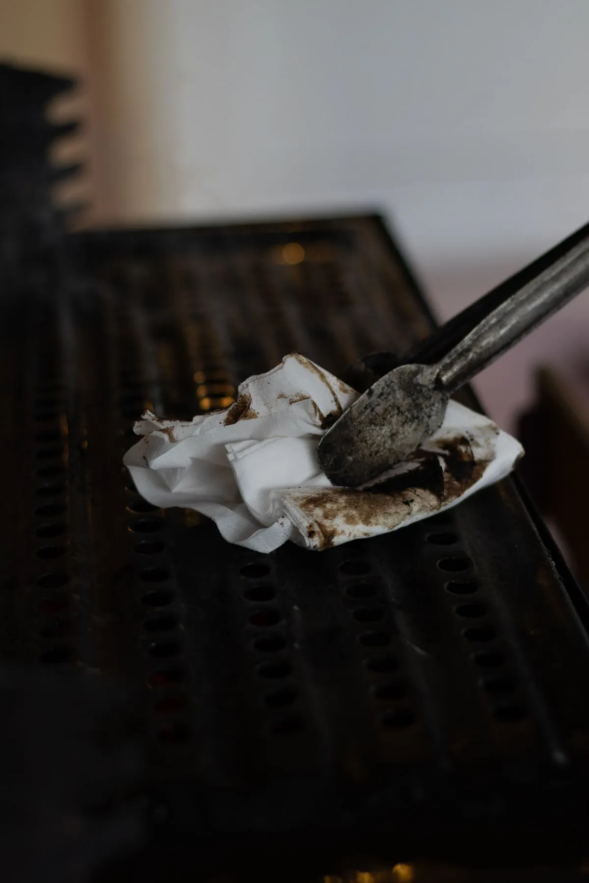 A grill grate being wiped with paper