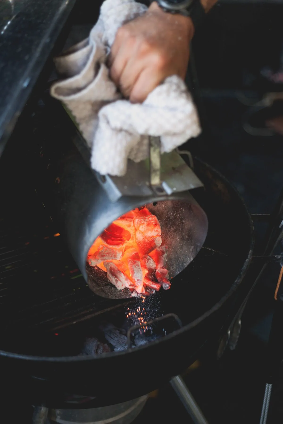 Pouring charcoal into an outdoor grill