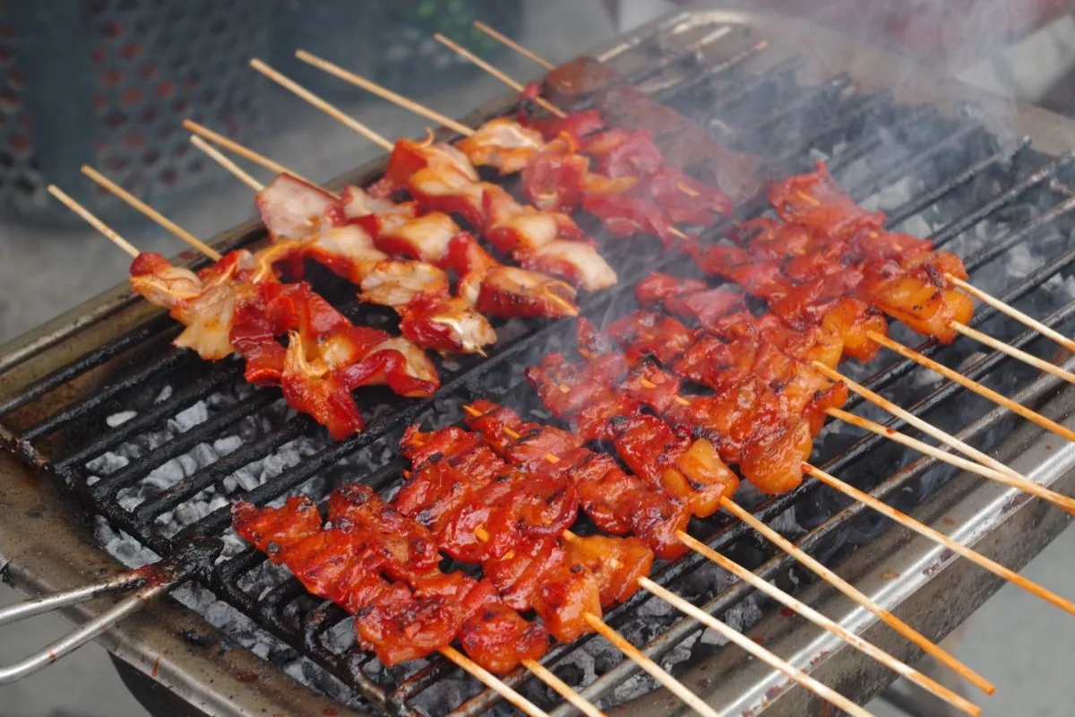 Chicken pieces cooking on skewers